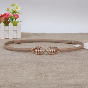 Detailed view of the elegant women's thin beige leather belt with gold pearl leaf buckle.