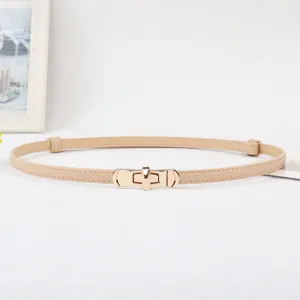 Detail view of a slim beige women belt with a gold tone metal lock buckle for dresses.