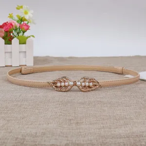 Close-up detail of the elegant thin leather waist belt with gold leaf pearl buckle.