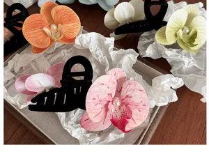 Détail de grandes pinces à cheveux orchidée avec perles dans un plateau en bois