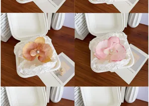 Detail view of pink and orange orchid hair clips with pearl centers in a creative box
