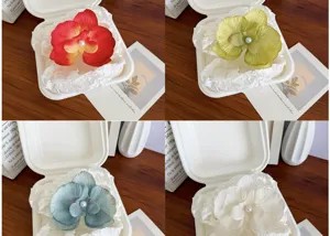 Detailed view of handmade orchid hair clips in four colors with faux pearl centers.