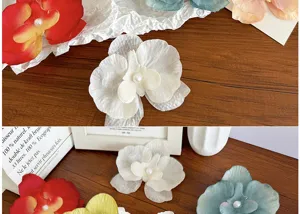 Detailed view of colorful phalaenopsis orchid hair clips with pearl centers on a wood table
