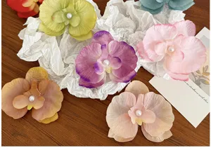 Aesthetic butterfly orchid hair clips with pearls in multiple colors on crumpled paper.