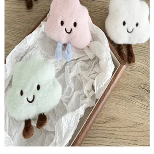 Broches mignonnes et artisanales en peluche en forme de nuage présentées dans un plateau en bois.