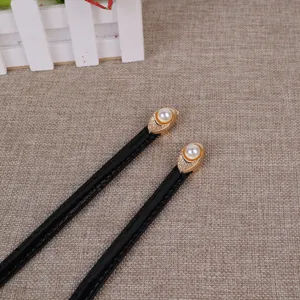 Close-up detail van de elegante zwarte smalle riem met gouden parelgesp tips voor jurken.