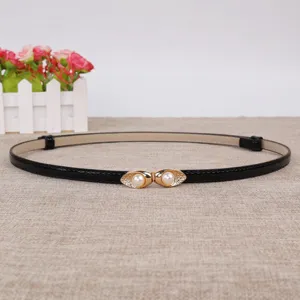 Gedetailleerd overzicht van de smalle zwarte riem met elegante gouden parelgesp.
