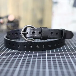Close-up of black leather belt featuring star cutouts and a round metal buckle detail.