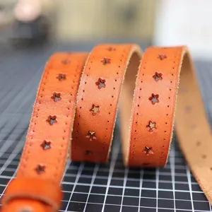 Close-up detail view of the brown leather belt featuring unique star-shaped cutouts and fine stitching.