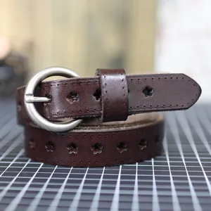 Women brown leather belt with metal round buckle and star cutout design for jeans and dresses.