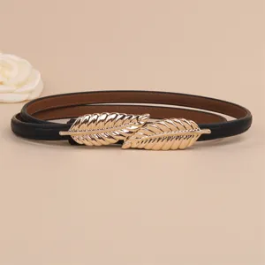 Close-up detail of women's thin black leather belt featuring a sleek gold leaf buckle design.