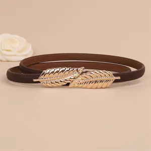 Detailed view of the brown leather thin belt with elegant gold leaf buckle closeup.