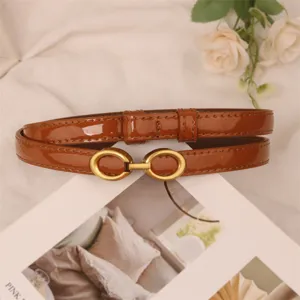 Detailed view of women thin brown patent leather belt with elegant gold double ring buckle.