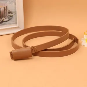 Close-up detail of a smooth brown cowhide narrow belt for women on a peach background