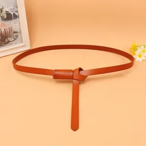 Close-up detail of a minimalist brown slim leather belt for women's summer dresses
