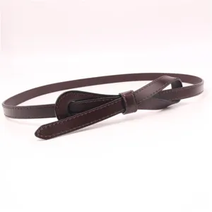 Détail de ceinture fine en cuir marron foncé, nœud papillon élégant pour décorer la taille.