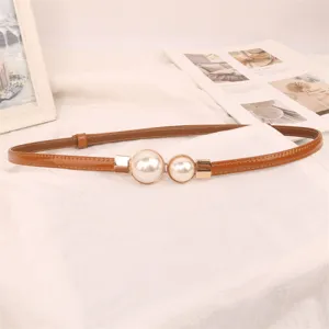 Detail shot of elegant thin brown leather dress belt with white pearl buckle decoration