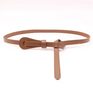 Détail de ceinture en cuir marron fin pour femme, design noué élégant pour robe et pull taille.