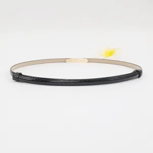 Minimalistische dunne zwarte laklederen dames tailleceintuur met gouden metalen gesp.