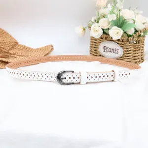 Close up of white hollow leather belt detail, showing exquisite pattern and metal buckle.