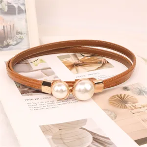 Detailed macro shot of the elegant double pearl buckle on a thin brown belt
