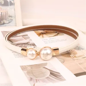 Detail view of a thin white leather belt with an elegant large double pearl buckle.