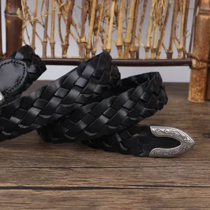 Close-up of a vintage black braided leather belt featuring an ornate engraved silver metal tip.