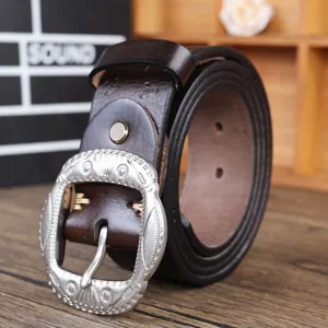 Brown vintage leather belt detail showcasing the intricate carved silver buckle and texture.