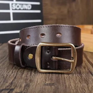 Close-up of a genuine leather men belt in dark brown with a vintage brass metal pin buckle.