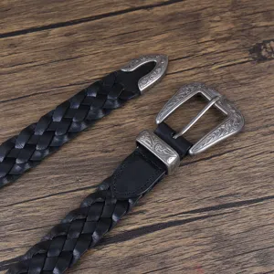 Close-up of vintage braided black leather belt with engraved metal buckle detail.