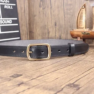 Close-up detail view of black genuine leather belt with retro brass metal pin buckle craft.