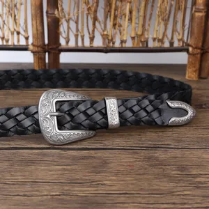 Detailed view of an ornate vintage silver buckle on a black braided leather belt for women