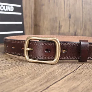 Close-up detail of the vintage brown leather belt with retro brass metal pin buckle texture.