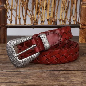 Close-up of retro reddish-brown woven leather belt with ornate silver floral buckle.