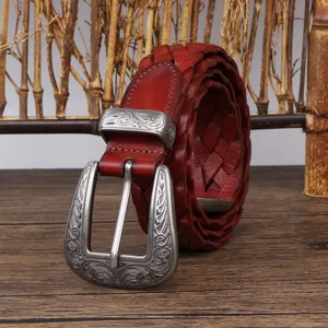 Detail of ornate engraved silver buckle on a reddish-brown braided leather belt.