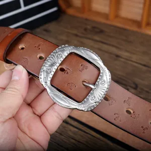 Close up view of brown leather belt with ornate silver pin buckle and embossed pattern details.