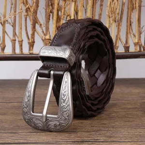 Macro view of vintage brown braided leather belt featuring an ornate engraved silver buckle