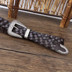 Close-up of vintage brown woven leather belt with intricate silver engraved buckle