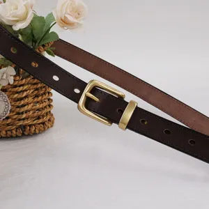Gros plan détaillé de la ceinture en cuir marron vintage avec une boucle en laiton classique.
