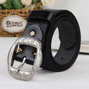 Close-up detail shot of a black vintage leather belt with an ornate silver carved buckle.