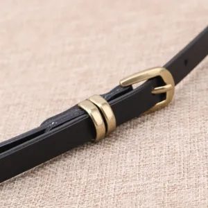 Primer plano detallado de un cinturón de cuero negro para mujer con hebilla de latón elegante.