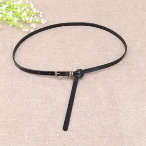 Detalle de un cinturón fino negro para mujer con hebilla metálica y nudo elegante.