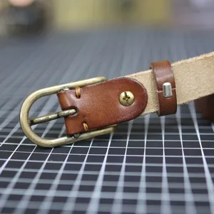Detailed view of brown leather belt with brass buckle, high quality crafted narrow belt.