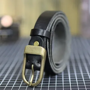 Detail of women's black leather belt with vintage bronze buckle, soft durable material.