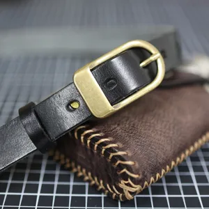 Detail view of a stylish minimalist women's black leather belt with a vintage brass buckle.
