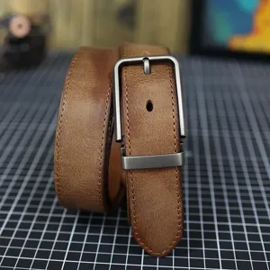 Primo piano dettaglio della cintura uomo in vera pelle marrone vintage con fibbia.
