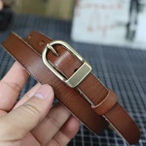 Close-up detail of genuine leather thin belt with retro metal buckle, fine texture.