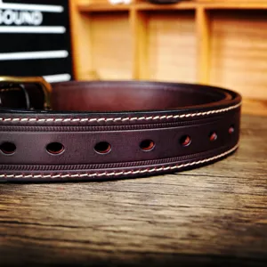 Vue détail ceinture cuir véritable homme marron foncé style vintage avec coutures blanches.