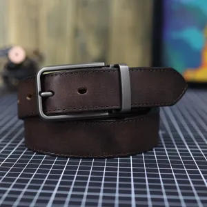Primo piano di una cintura da uomo in vera pelle marrone scuro con robusta fibbia ad ardiglione.