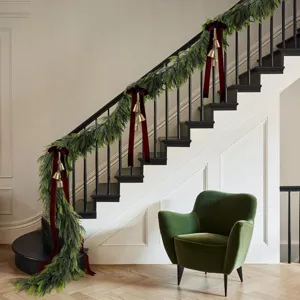 Üppige Norfolk-Kieferngirlande mit roten Samtschleifen und Goldglocken an der Treppe